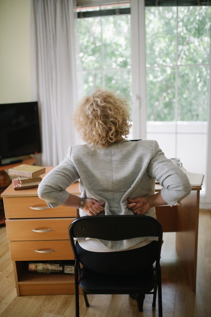 Senior woman holding her lower back in pain at home